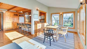Une cuisine spacieuse avec des meubles en bois, un coin repas comprenant une table et des chaises, et de grandes fenêtres qui laissent entrer la lumière naturelle.