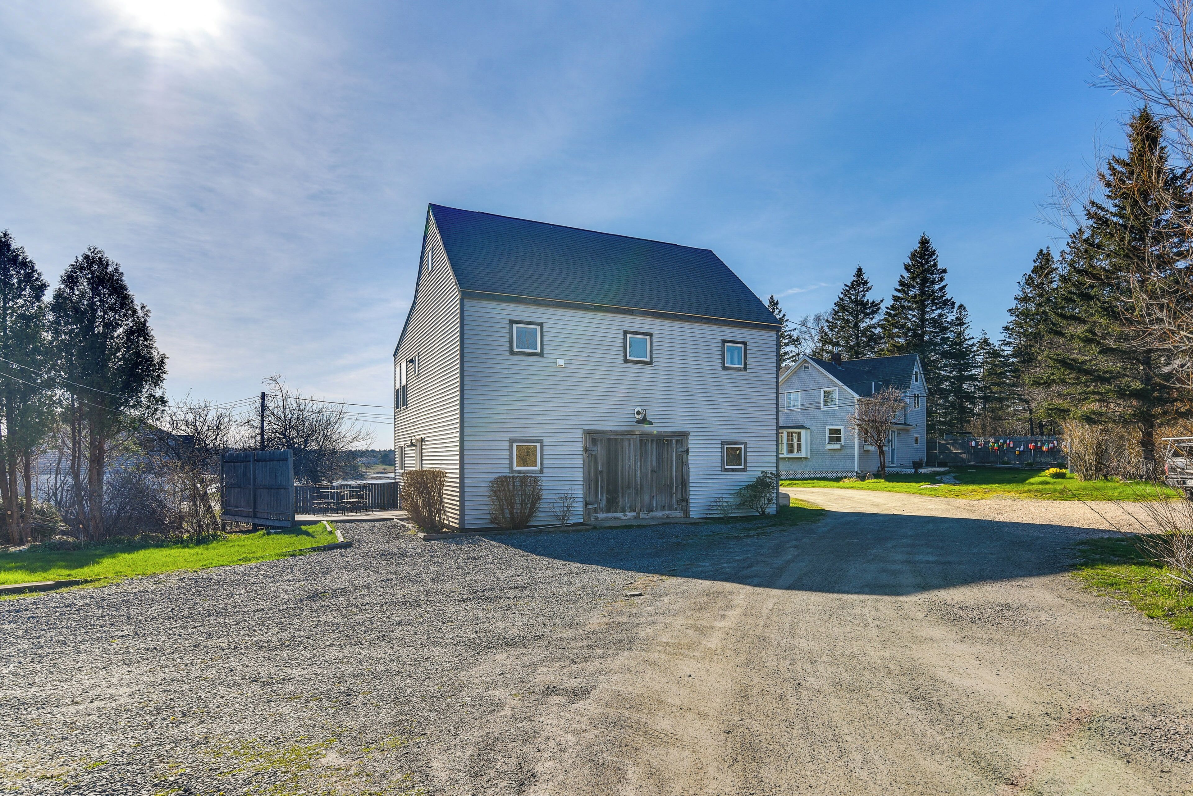 A two-story house with a gravel driveway and a metal fence.