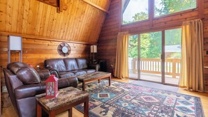 Ein gemütliches Blockhaus-Interieur mit einem Ledersofa, einem Holztisch und einem gemusterten Teppich.