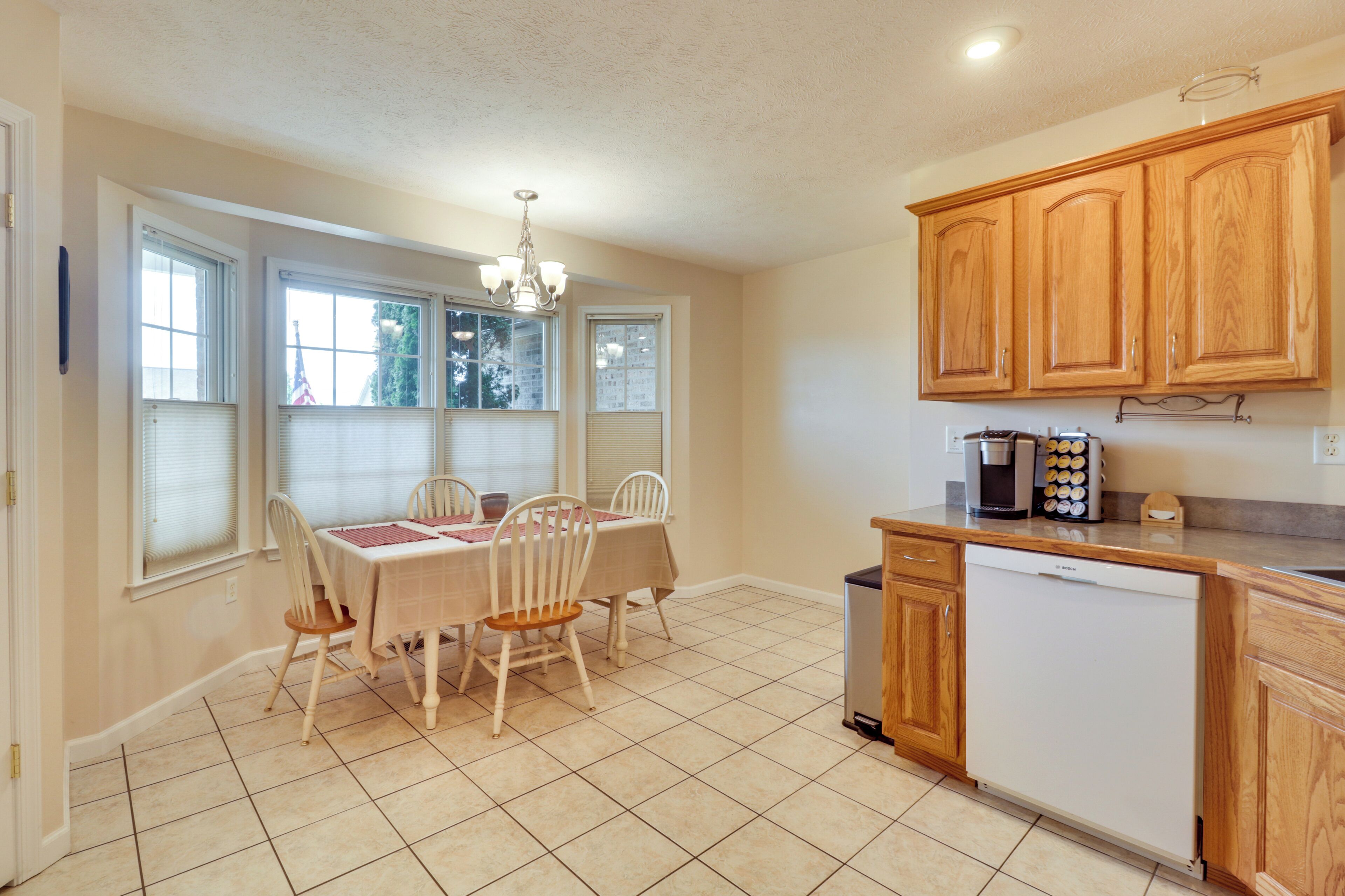 A kitchen with wooden cabinets, a dishwasher, and a dining area with a table and chairs.