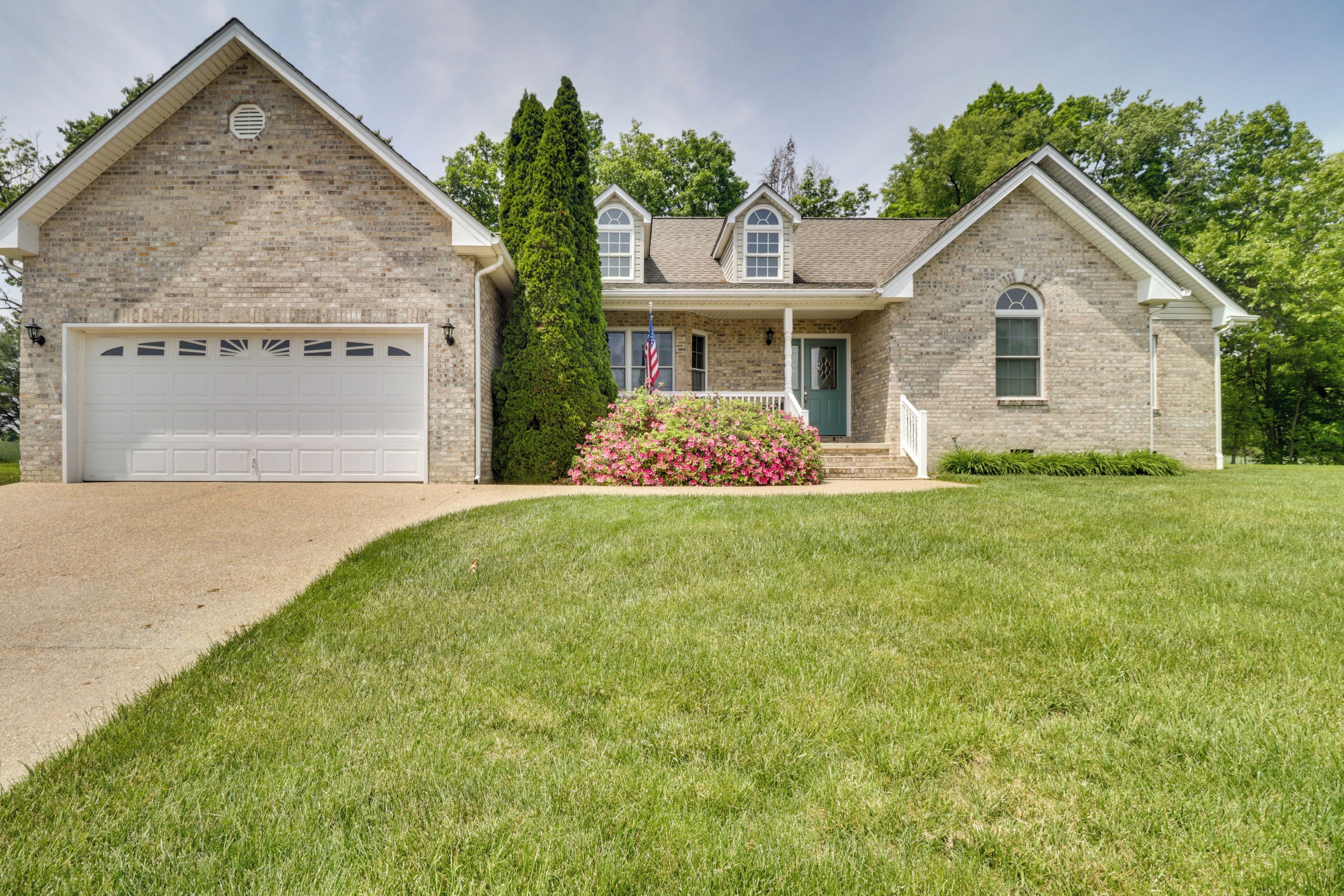 A two-story house with a brick facade, a white garage door, and a well-maintained lawn.