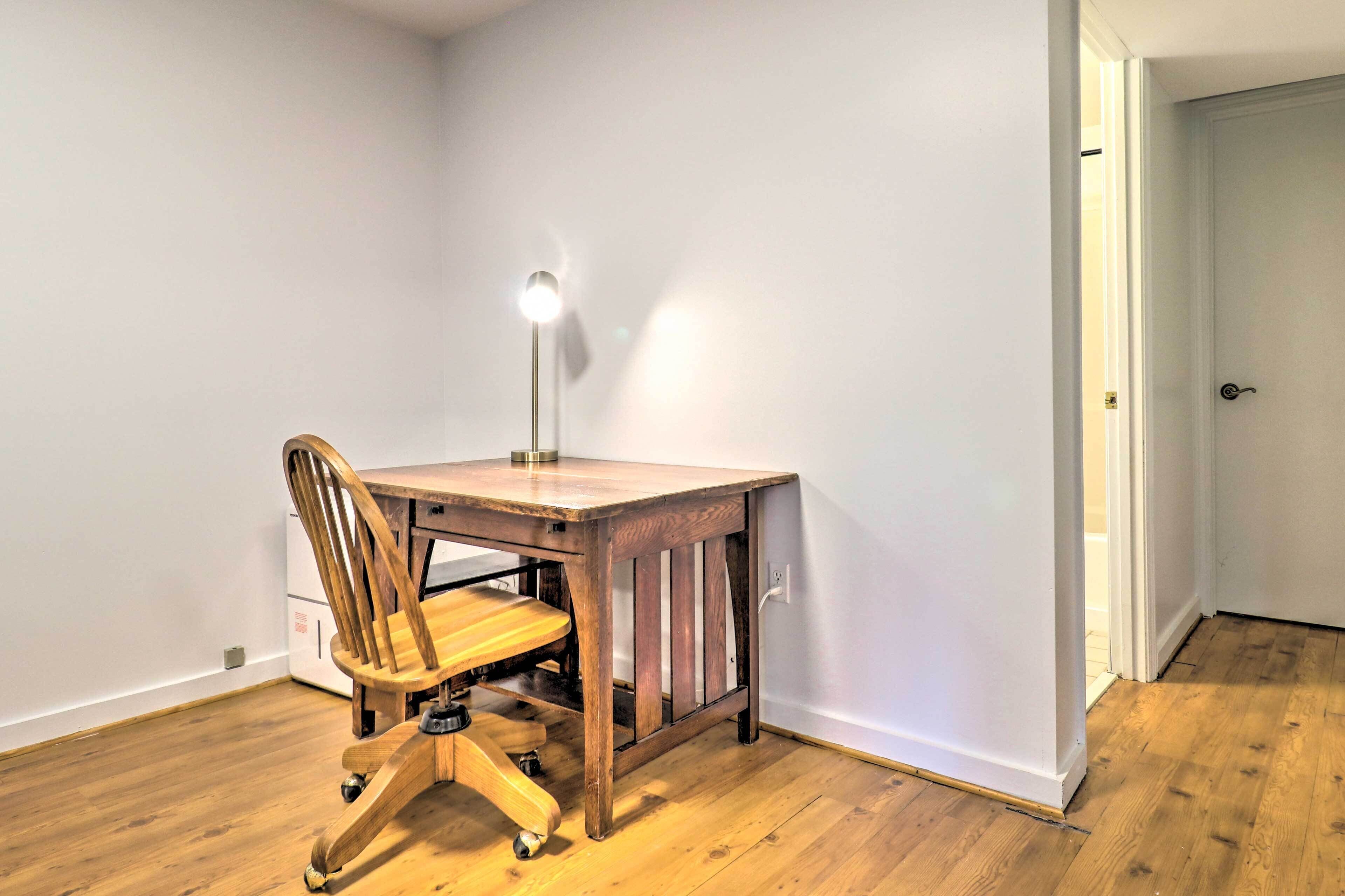 Une petite pièce, bien rangée, avec un bureau et une chaise en bois, une lampe et une porte.