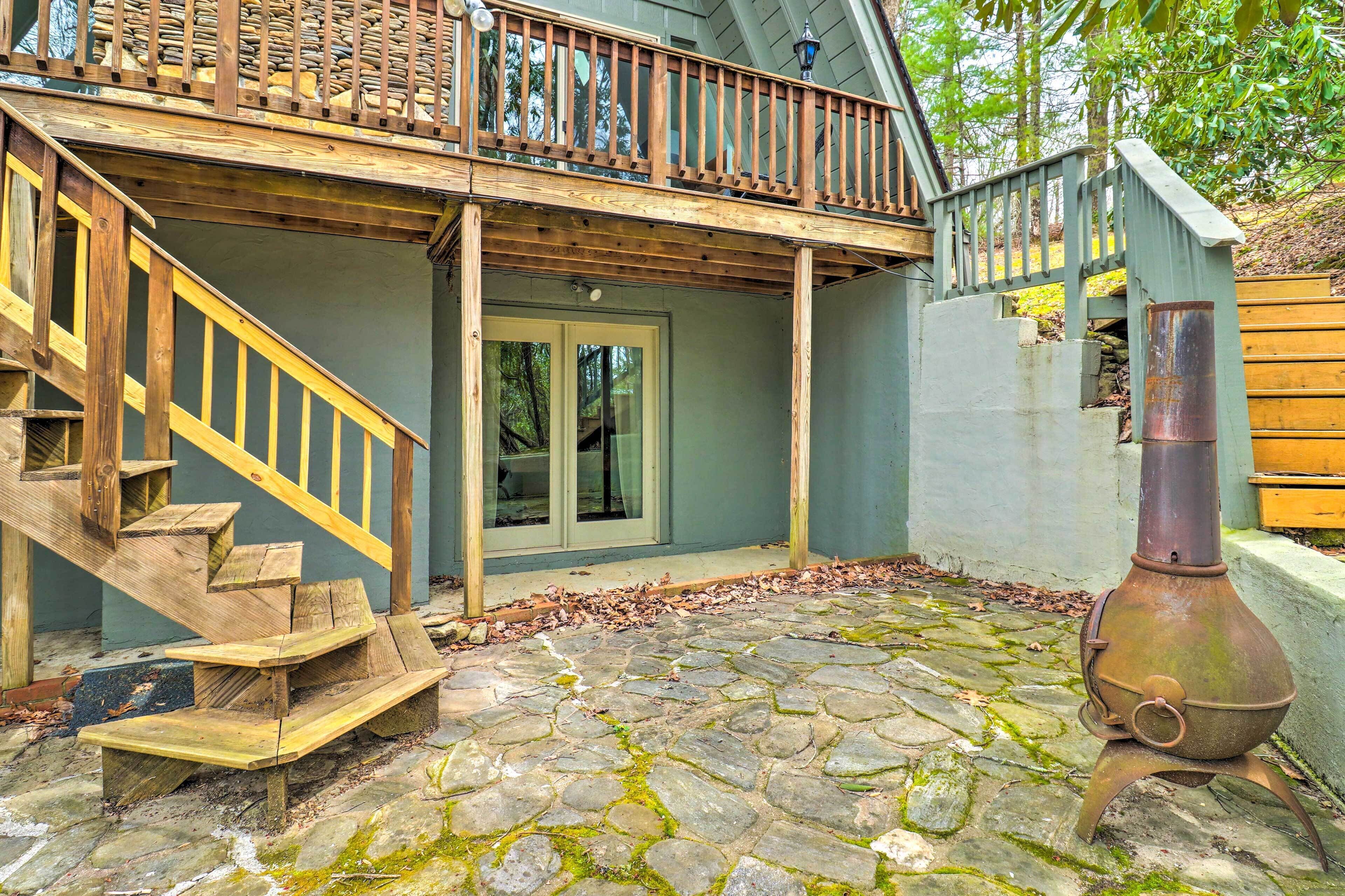 Une terrasse dallée de pierres, avec un escalier en bois menant à un balcon.