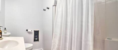 A bathroom with a white sink, toilet, and shower curtain.