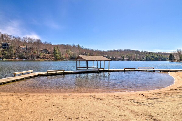 A lakeside beach with a wooden dock and benches, surrounded by trees and buildings. - Amazing A-frame w/ Private Hiking + Amenities (Brevard)
