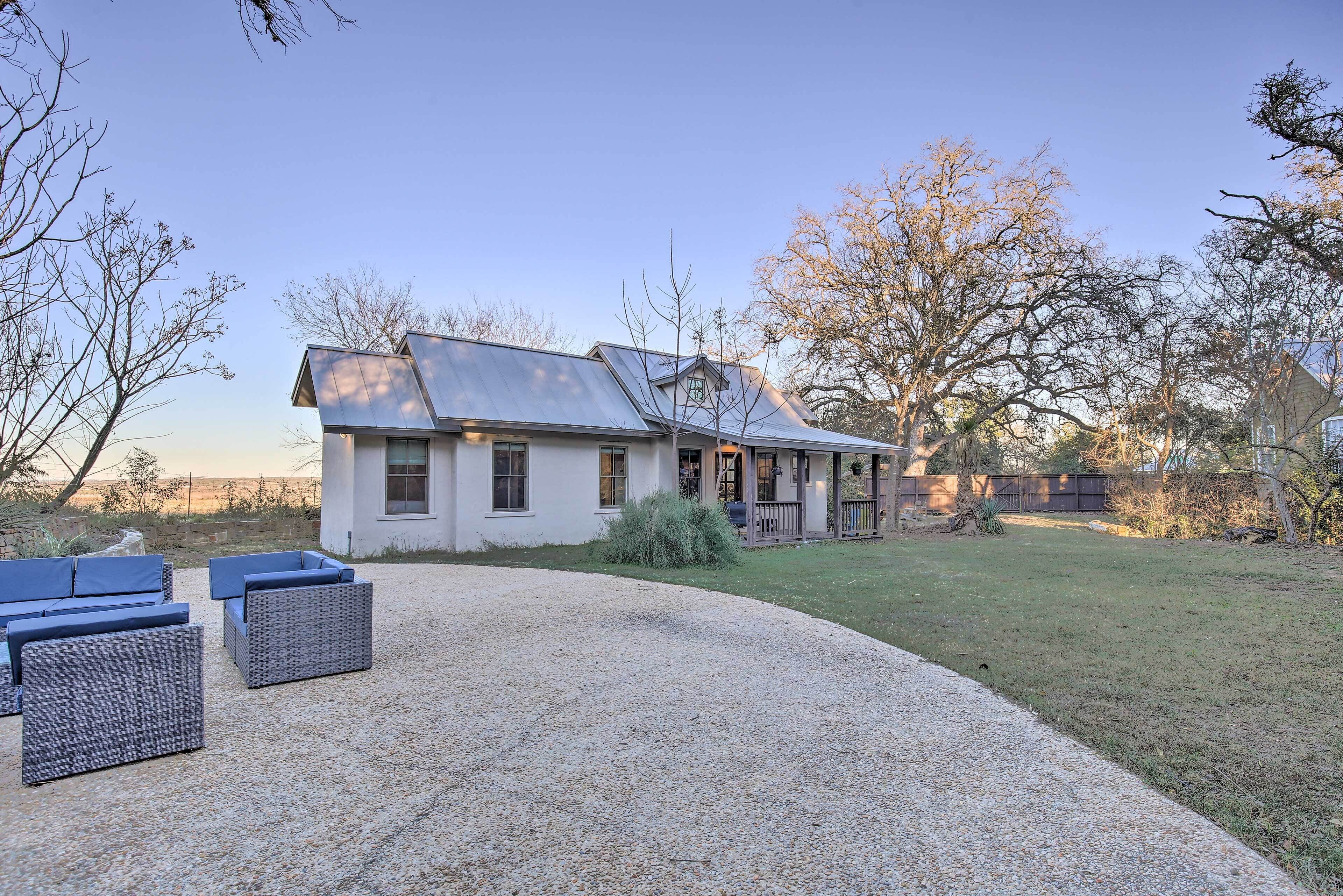 A modern house with a gravel driveway, outdoor seating area, and a well-maintained lawn.