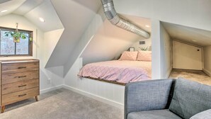 A bedroom with a sloped ceiling, a bed, a dresser, and a chair. - Charming Family Cottage Close to San Antonio (Castroville)