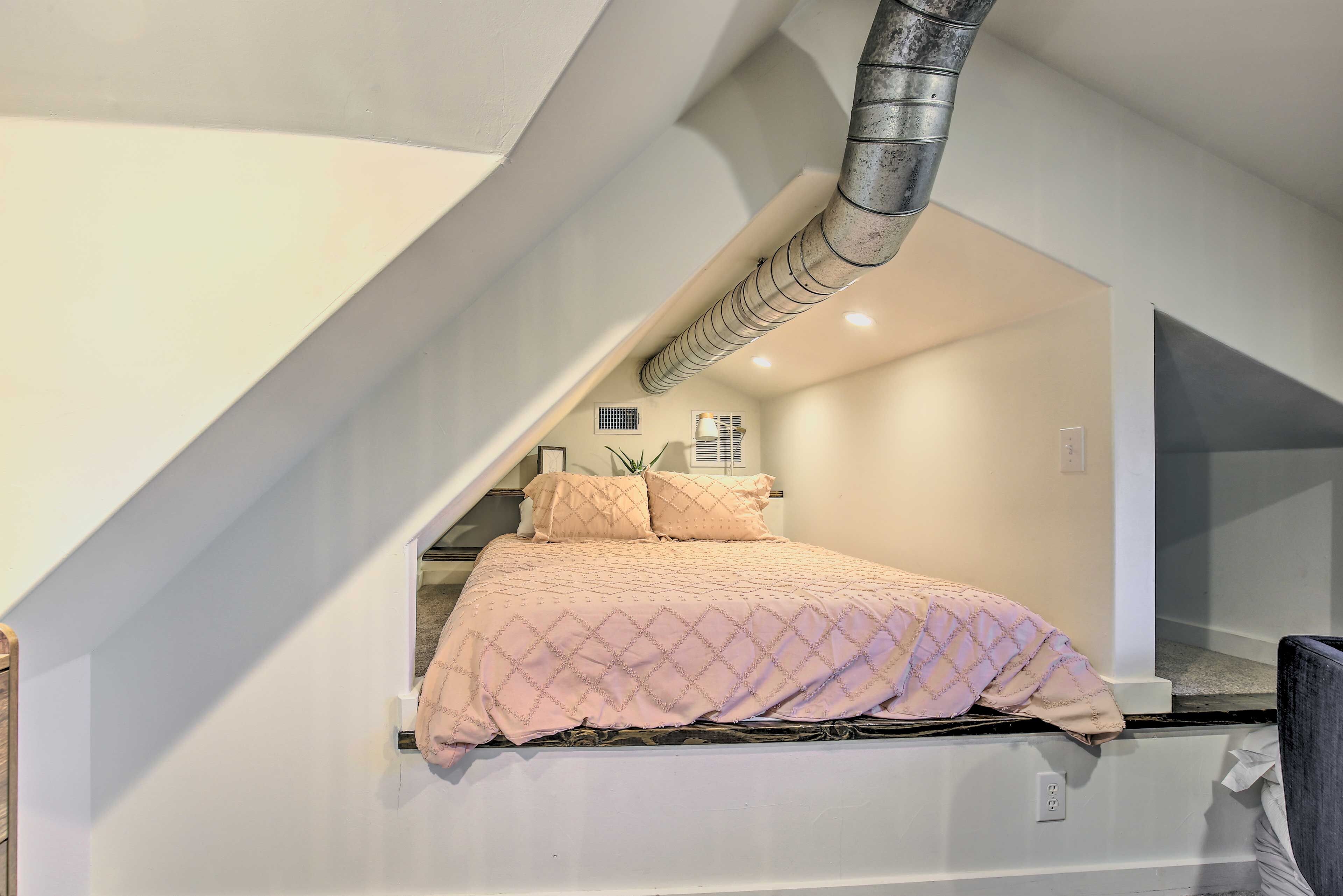 A bedroom with a bed, a window, and a ventilation duct.