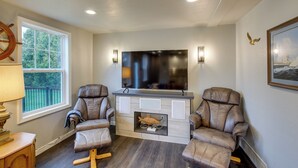 Una sala de estar con dos sillones de cuero, un televisor de pantalla plana y una chimenea.