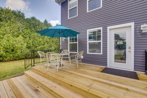 A wooden deck with outdoor furniture and a teal umbrella.
