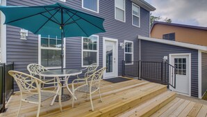 Una terraza de madera con mobiliario exterior y un gran paraguas.