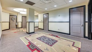 A hotel hallway with carpeted floors, doors, and a light fixture. - Heart of Dtwn Omaha: Historical Apt w/ Perks (Omaha)