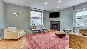 A modern living room with a fireplace, a large window, and a red rug. - Heart of Dtwn Omaha: Historical Apt w/ Perks (Omaha)