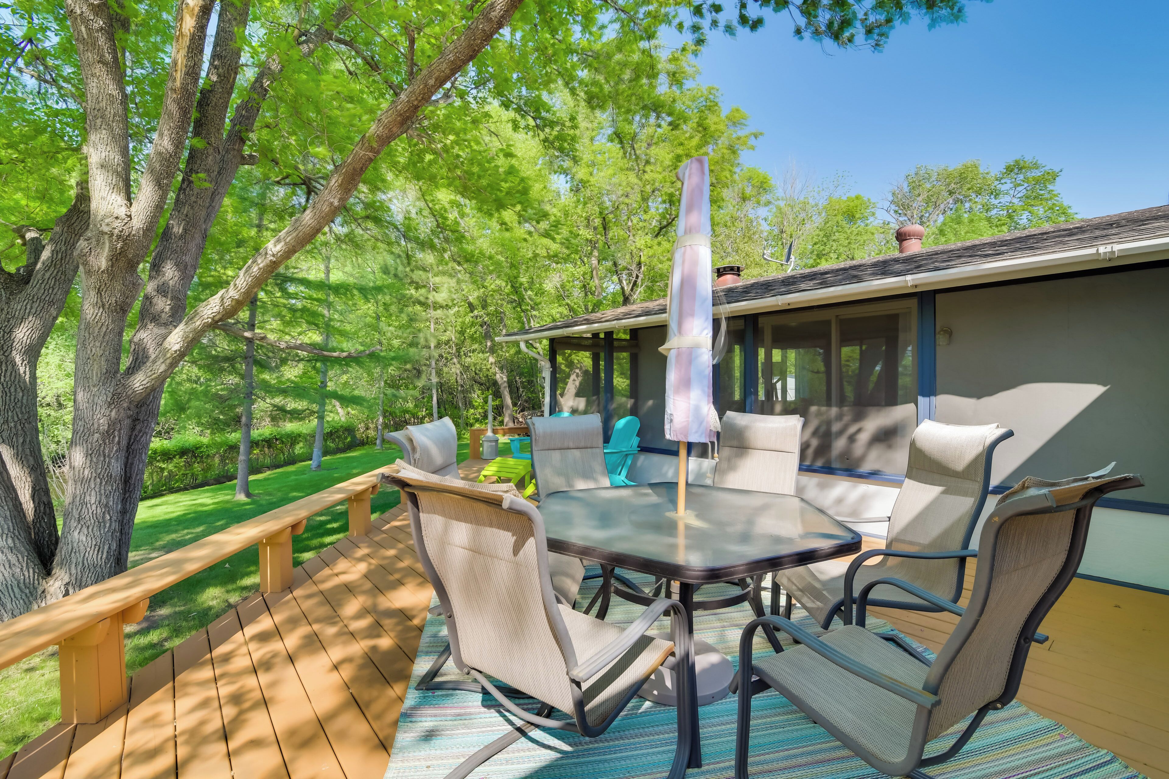 A deck with outdoor furniture, including a table and chairs, surrounded by trees.