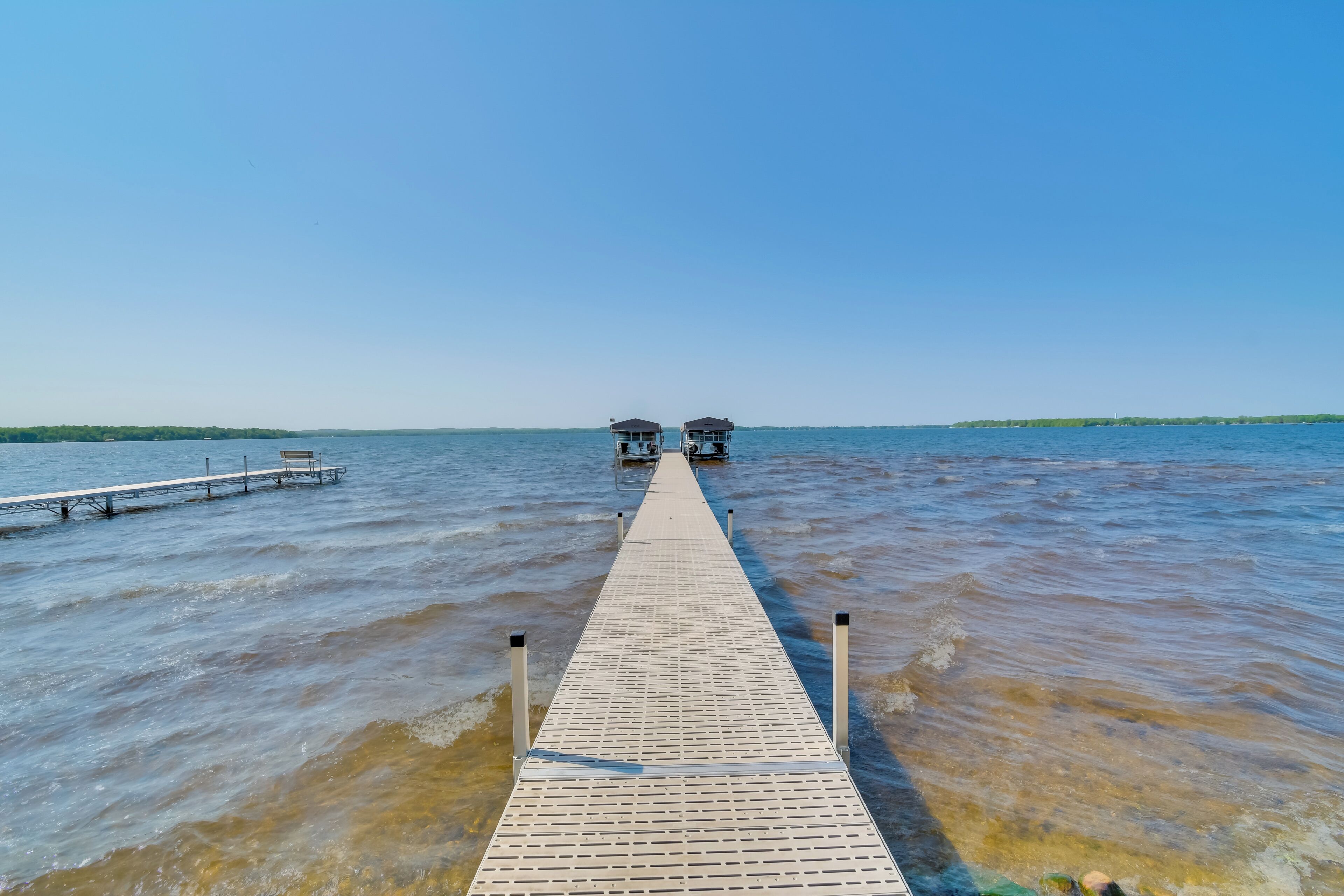 A wooden pier extending into a body of water with two structures at the end.