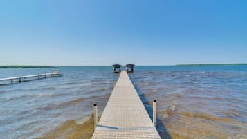 A wooden pier extending into a body of water with two structures at the end.