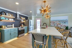 A modern kitchen with a central island, built-in appliances, and a large window with a beach view. - Home Rental on Detroit Lake: Dock, Game Room! (Detroit Lakes)