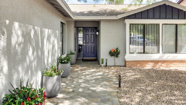 A house with a stone pathway leading to a dark blue door, potted plants, and a gravel area. - Tuscon Vacation Rental < 1 Mi to Golf Course! (Tucson)