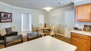A dining area with a white table and chairs, a painting on the wall, and a wooden cabinet. - Tuscon Vacation Rental < 1 Mi to Golf Course! (Tucson)