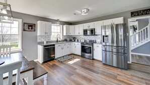 Una cocina moderna con armarios blancos, electrodomésticos de acero inoxidable y suelo de madera.