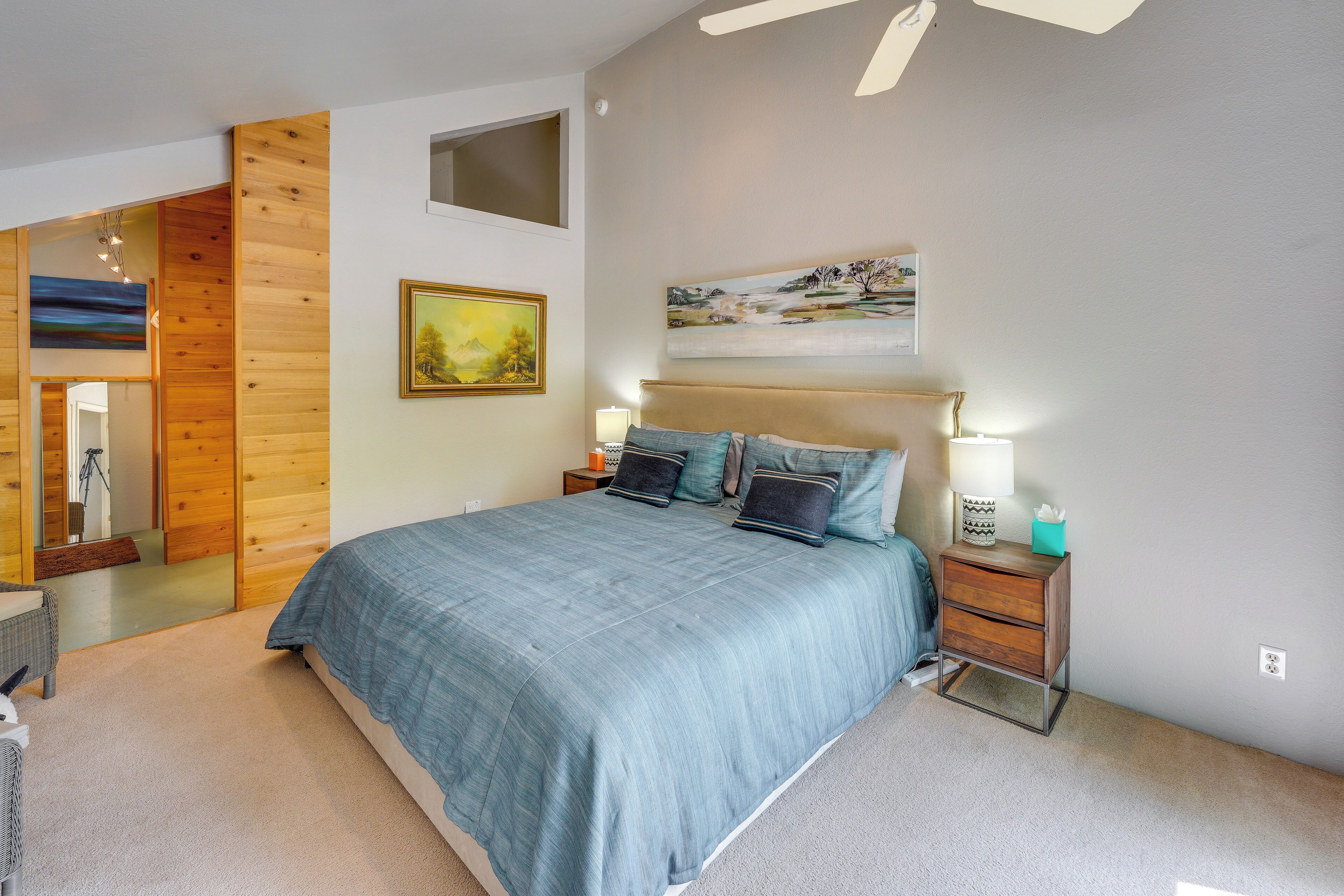 Une chambre à coucher avec un lit, des tables de chevet, un tableau et un panneau mural en bois.
