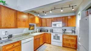 A kitchen with wooden cabinets, a microwave, a dishwasher, and a refrigerator. - Ketchum Mountain Retreat: Central Location! (Ketchum)