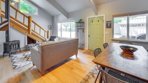 A spacious living area with a wooden staircase, a sofa, a dining table, and a large window. - Ketchum Mountain Retreat: Central Location! (Ketchum)