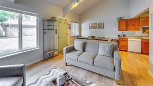 A modern living room with a grey sofa, a dining table, and a kitchen area with wooden cabinets and a dishwasher. - Ketchum Mountain Retreat: Central Location! (Ketchum)