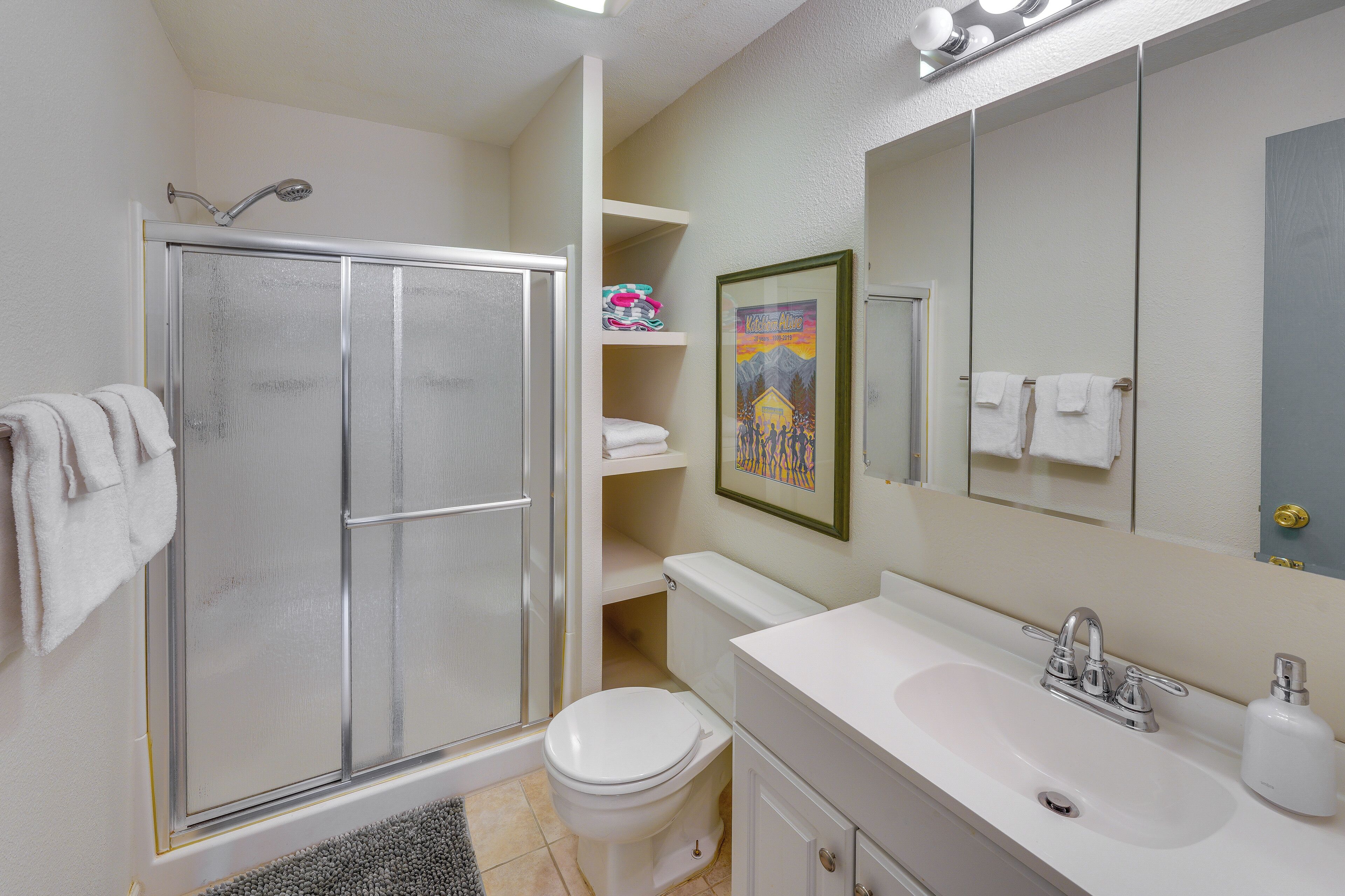 Een badkamer met douche, toilet, wastafel en een grote spiegel.