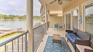 Un balcon avec vue sur un lac, un canapé en osier, une table et des chaises.