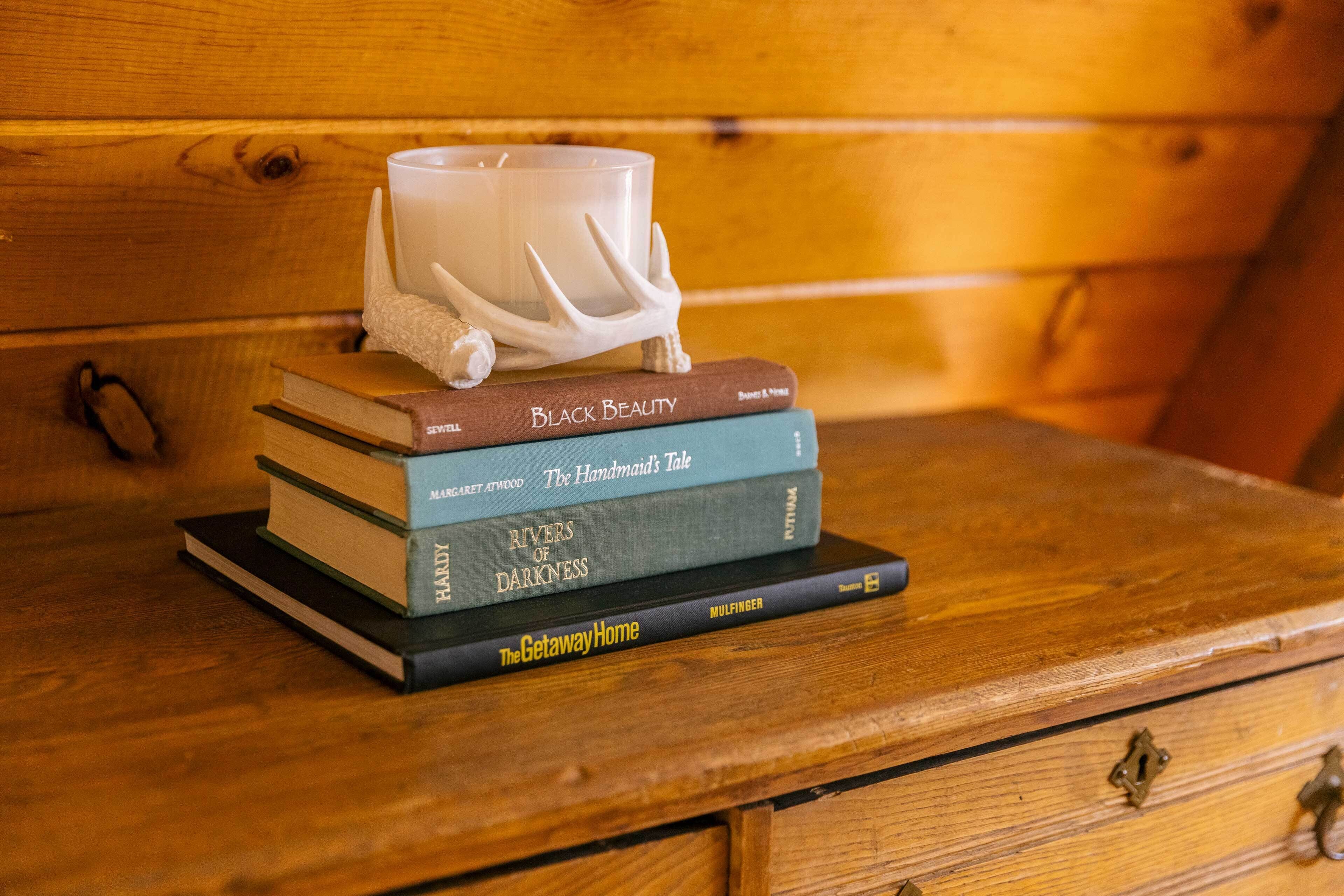 Una pila de libros sobre una superficie de madera, con una taza blanca encima.