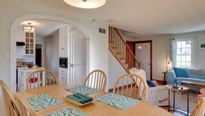 A dining area with a wooden table, chairs, and a kitchen in the background. - Walk to Village! Family-friendly Gem in East Burke (East Burke)