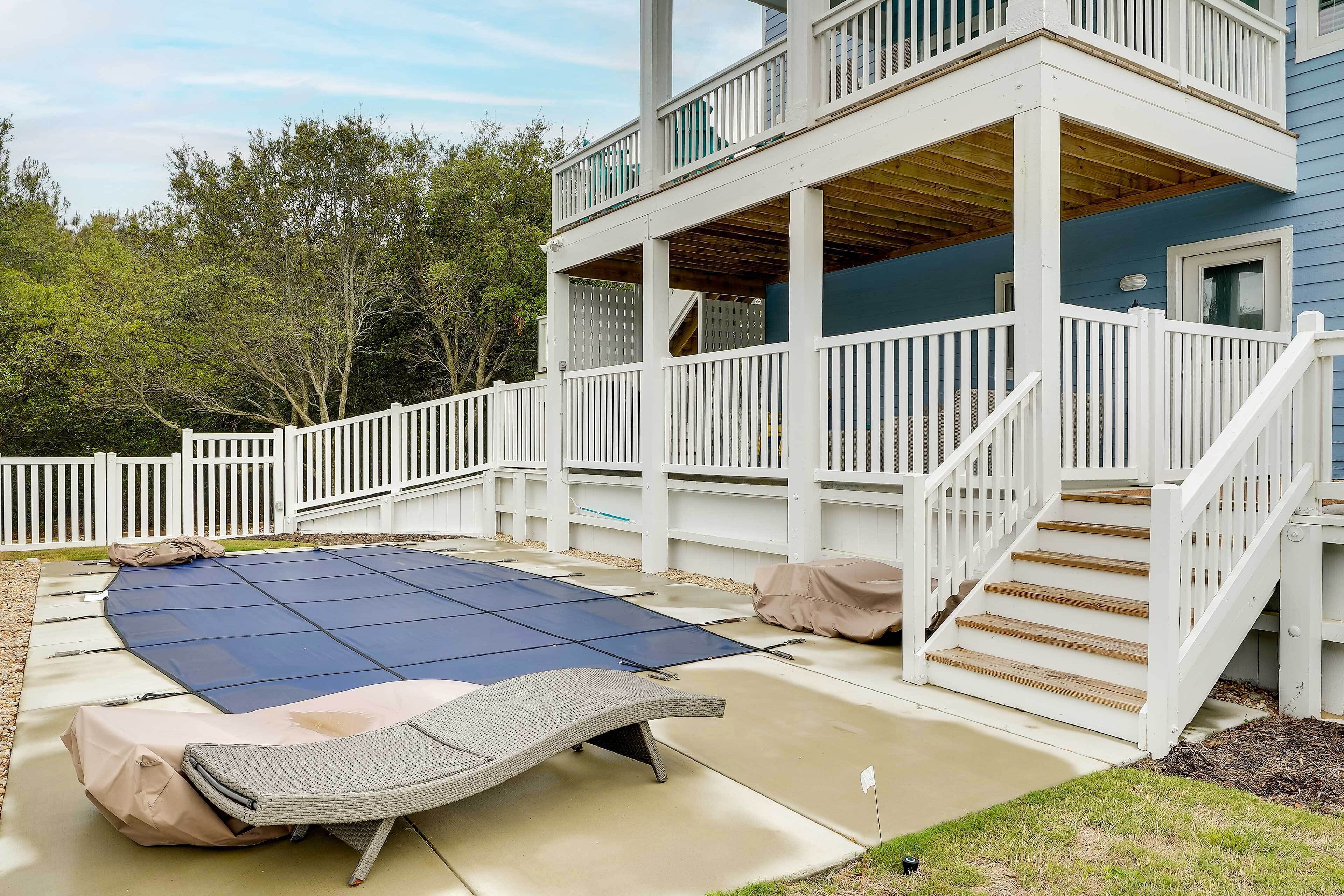 Une terrasse extérieure couverte avec un trampoline, un fauteuil de relaxation abrité et un escalier menant à un balcon situé à l’étage.