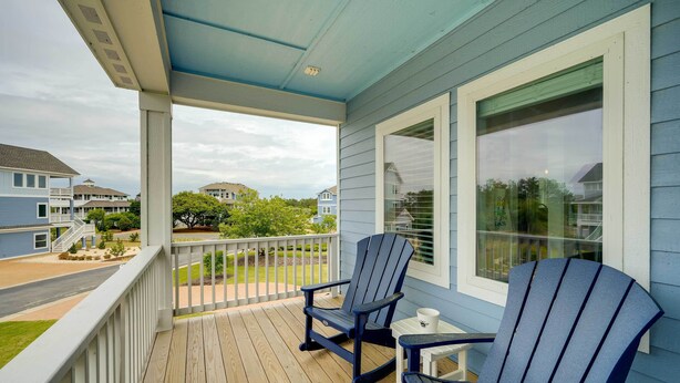 A covered porch with two Adirondack chairs, a small table, and a window with blinds. - Corolla Vacation Rental w/ Pool, Walk to Beach! (Corolla)