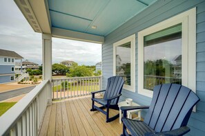A covered porch with two Adirondack chairs, a small table, and a window with blinds. - Corolla Vacation Rental w/ Pool, Walk to Beach! (Corolla)