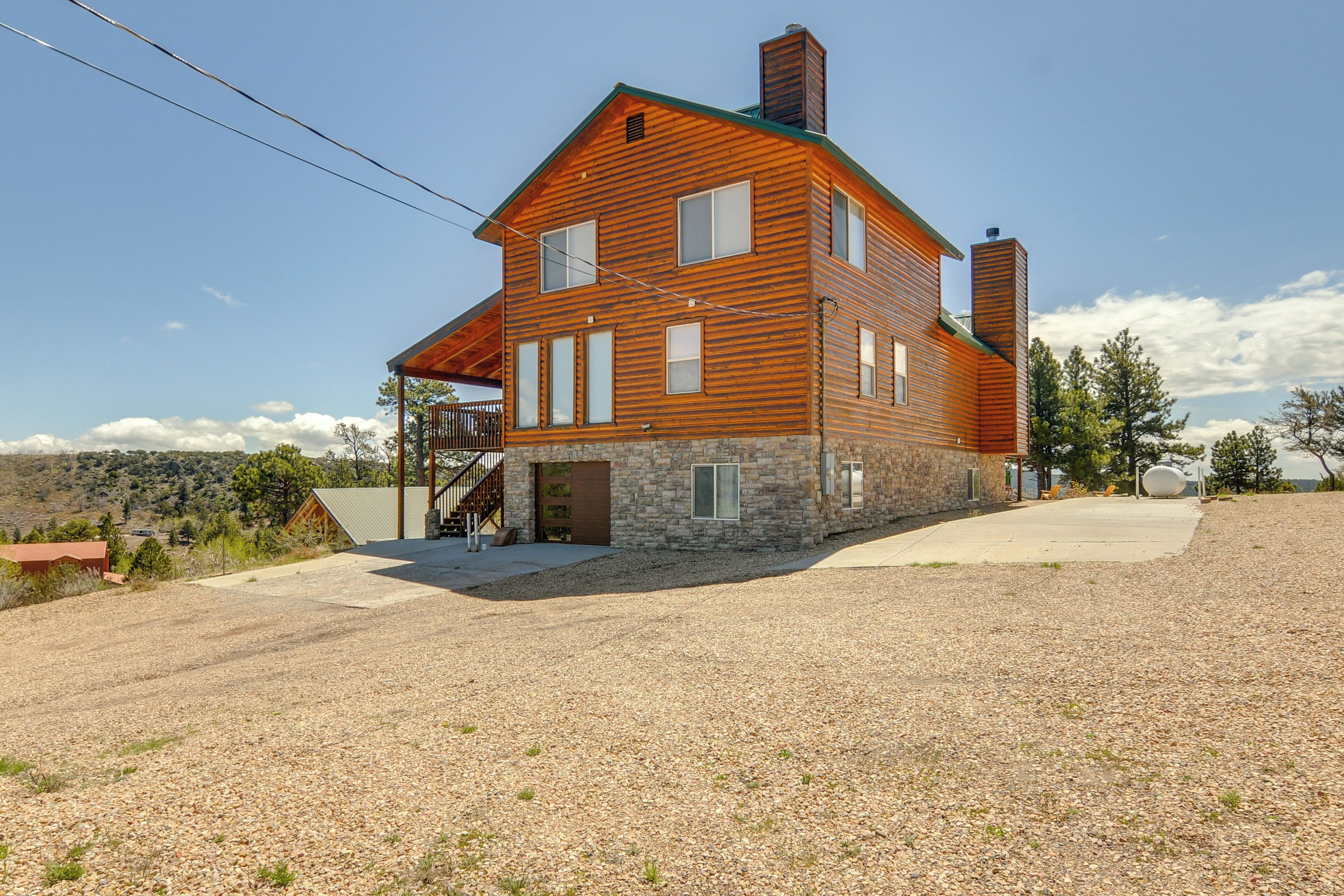 A two-story wooden house with a stone foundation, a covered porch, and a gravel driveway.