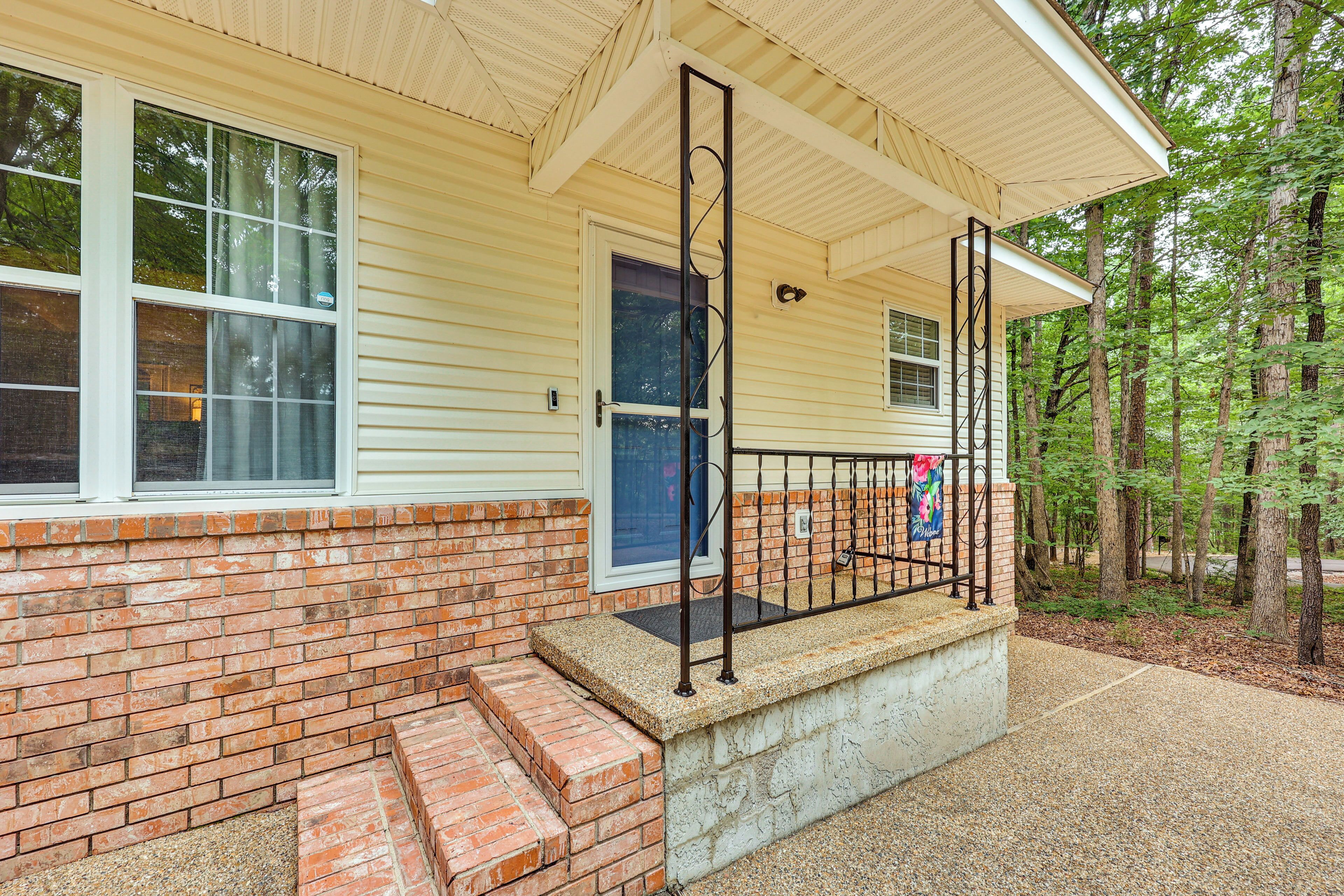 A building with a brick exterior, a blue door, and a concrete step leading to a porch with a metal railing.