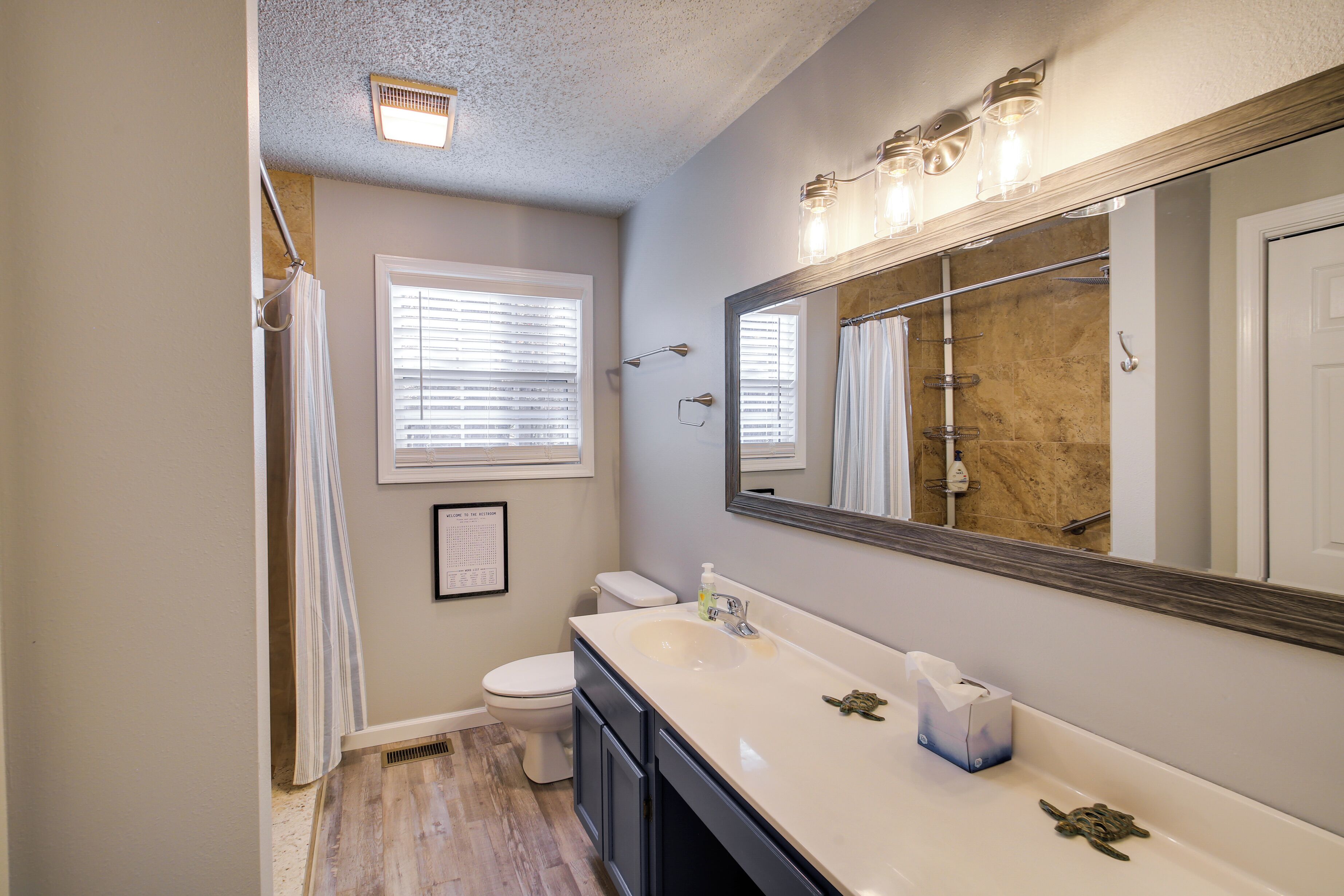 A bathroom with a white sink, a large mirror, a toilet, and a shower curtain.