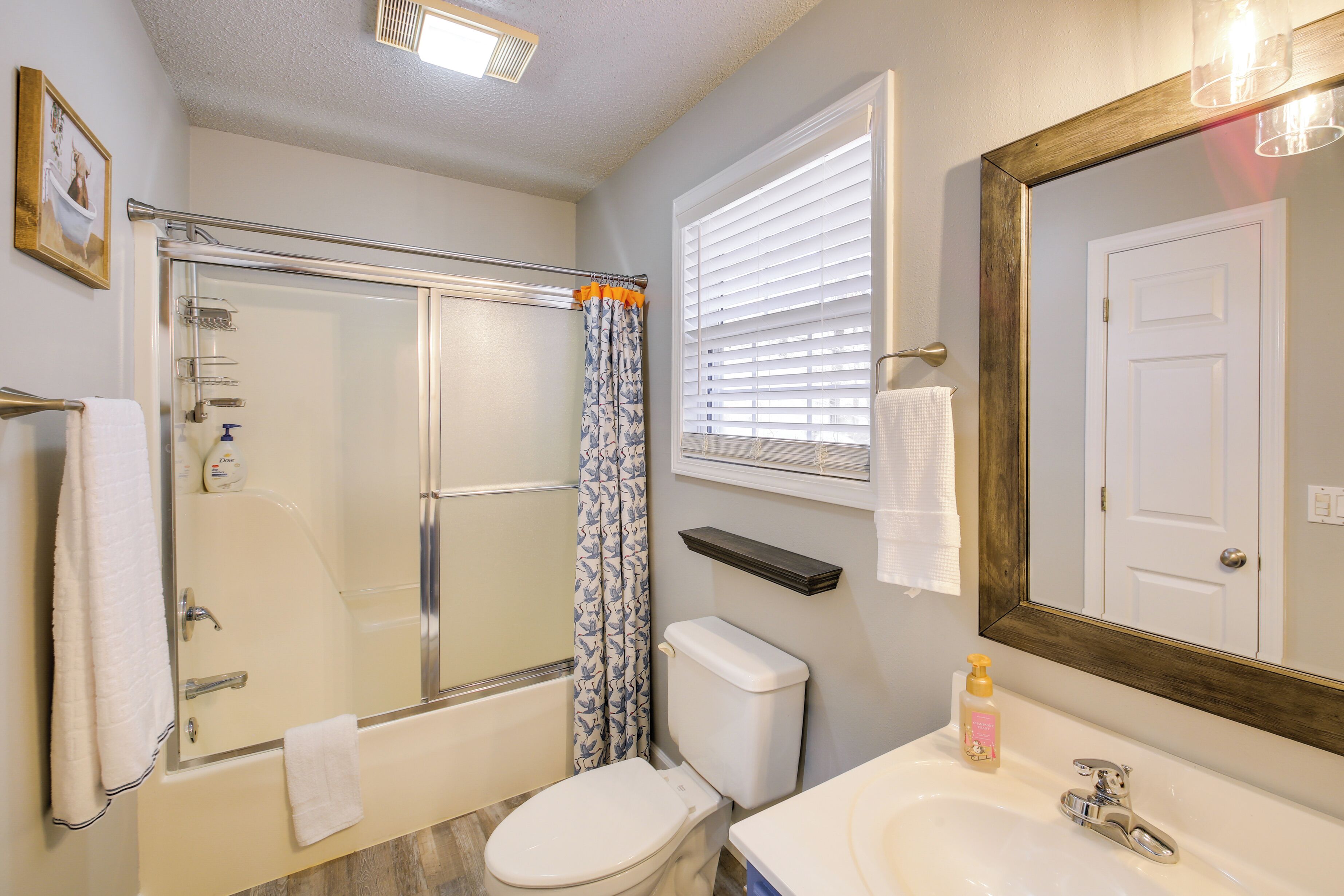A bathroom with a glass-enclosed shower, a toilet, a sink with a mirror, and a towel rack.