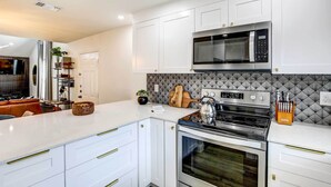 Una cocina moderna con armarios blancos, estufa de acero inoxidable y microondas.