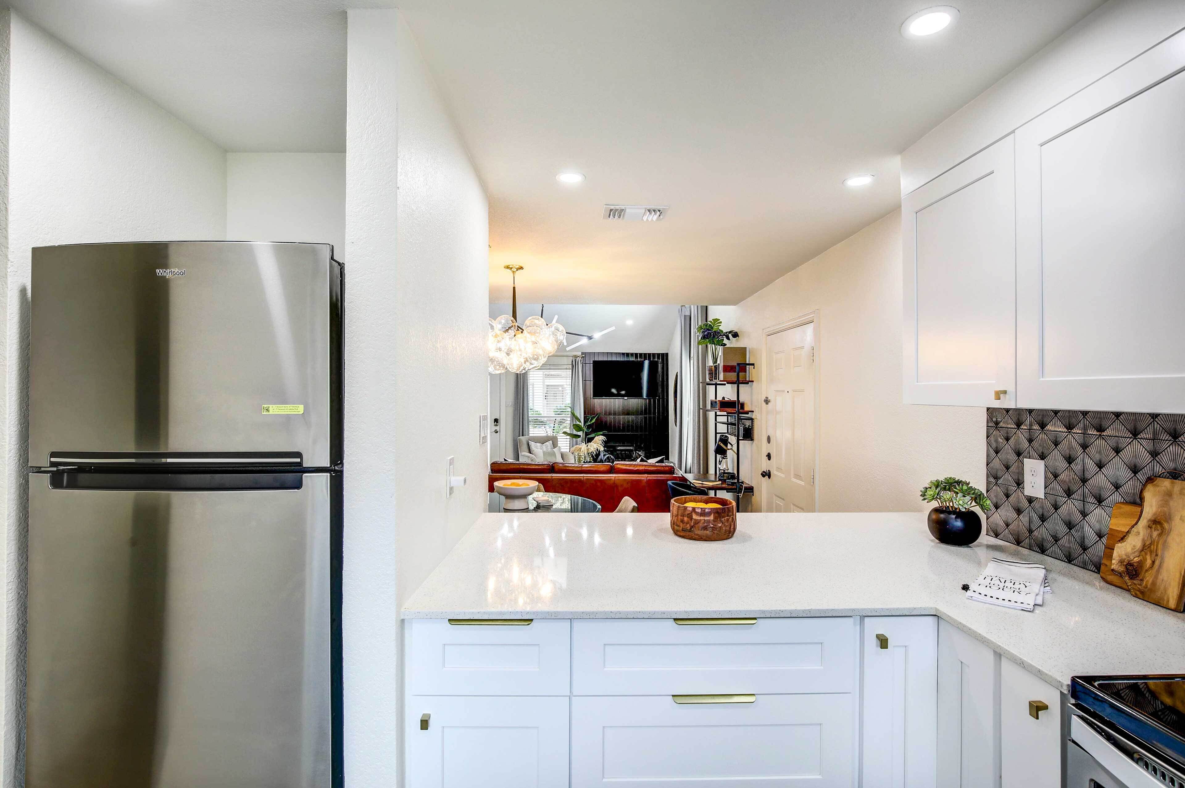 A modern kitchen with white cabinetry, a stainless steel refrigerator, and a built-in oven.