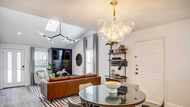 Una sala de estar moderna con una mesa de comedor de vidrio, sofá de cuero y una lámpara esférica original.