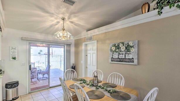 A dining area with a wooden table, white chairs, and a chandelier. - 2 Mi to Lake Havasu: Peaceful Home w/ Pool & Views (Lake Havasu City)