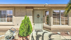 A house with a stucco exterior, a white door with a welcome mat, and a small green bush in front. - 2 Mi to Lake Havasu: Peaceful Home w/ Pool & Views (Lake Havasu City)