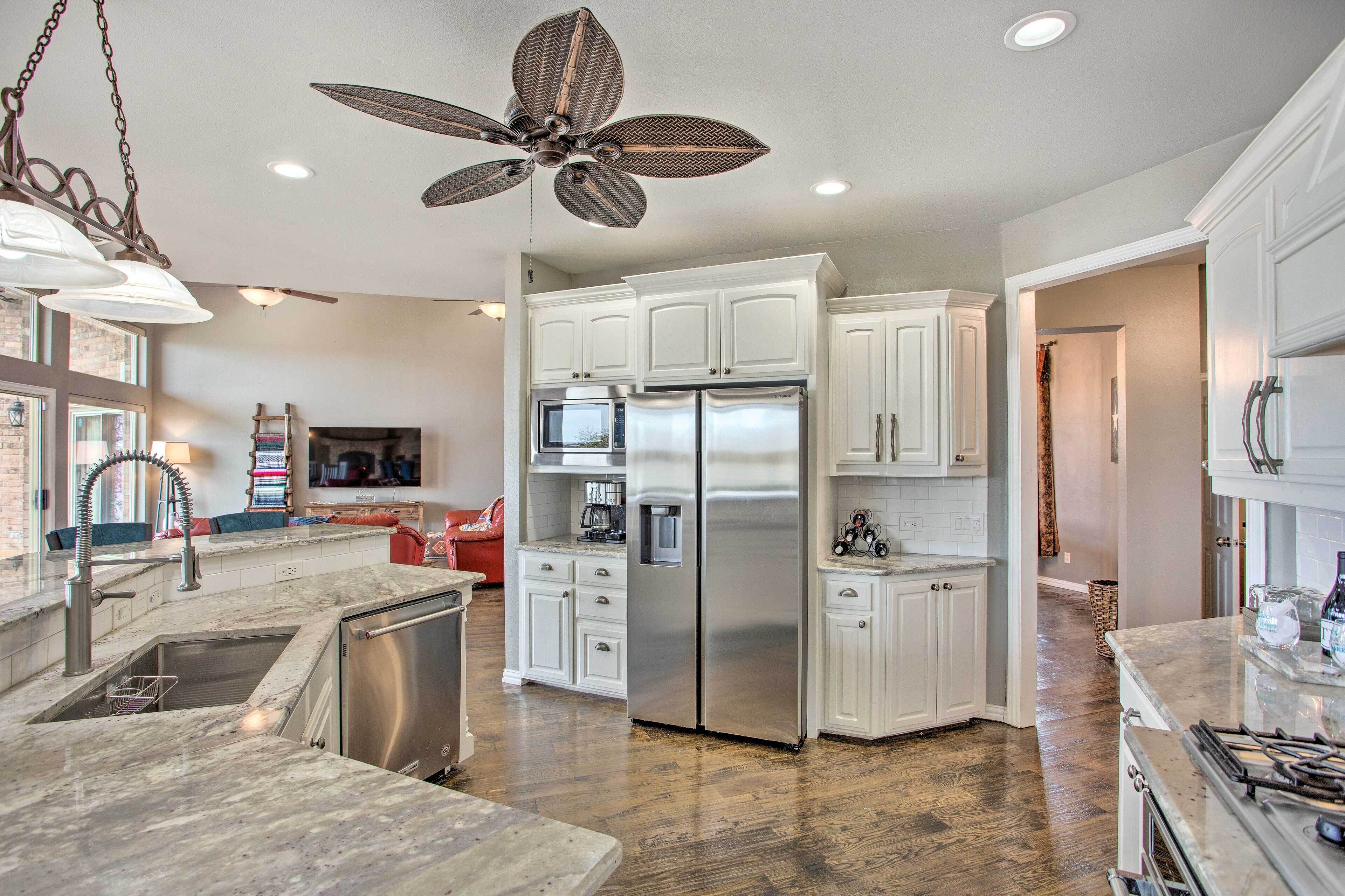 A modern kitchen with white cabinets, stainless steel appliances, and a wooden floor.