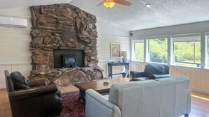 A living room with a stone fireplace, leather sofas, and a wooden coffee table. - Relaxing Cuchara Retreat on Cucharas River w/ View (La Veta)