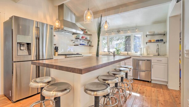 A modern kitchen with a central island, bar stools, stainless steel appliances, and pendant lighting. - Relaxing Cuchara Retreat on Cucharas River w/ View (La Veta)