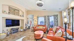 Ein großzügiges Wohnzimmer mit Kamin, Ledersofa und Flachbildfernseher.