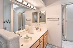 A modern bathroom with a double vanity, a large mirror, and a shower area.