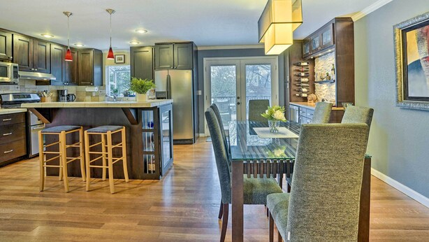 A modern kitchen with dark wood cabinets, a central island with stools, and pendant lighting. - Home w/ Hot Tub: 7 Mi to Edmonds Waterfront! (Lynnwood)